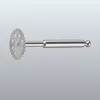Metal gear-like wheel with sharp teeth mounted on a long metal shaft with a rounded end.